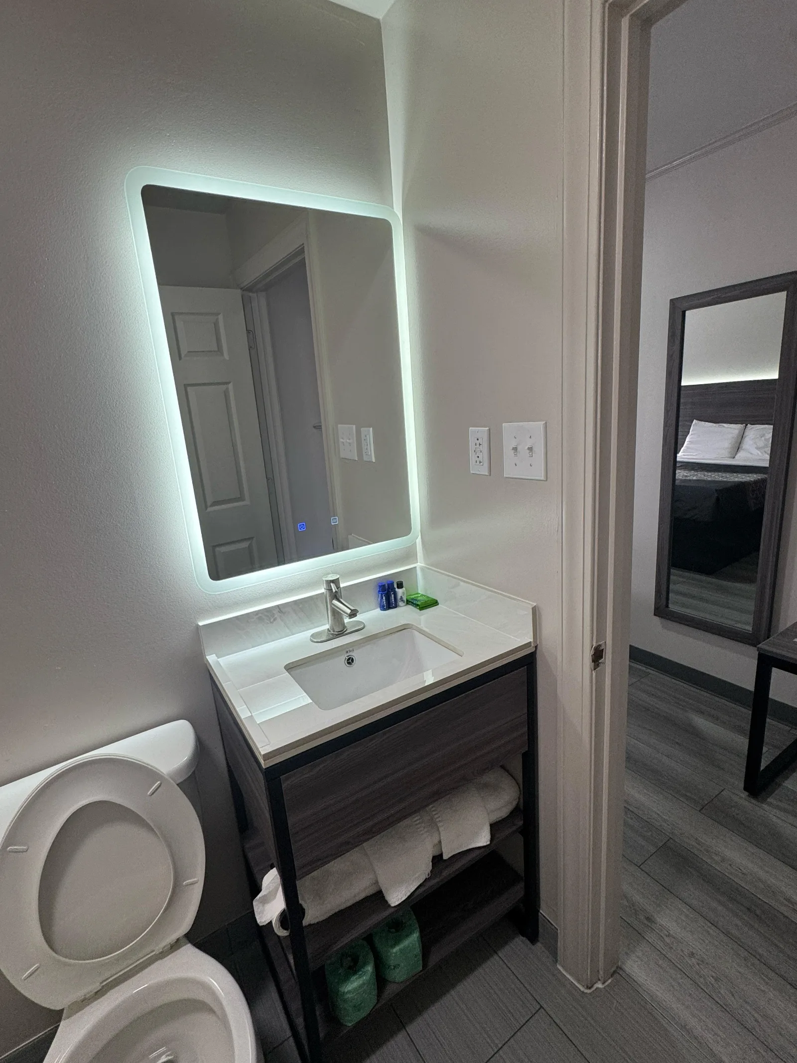 Modern bathroom with illuminated mirror, dark vanity, and white sink at Sportsman Inn