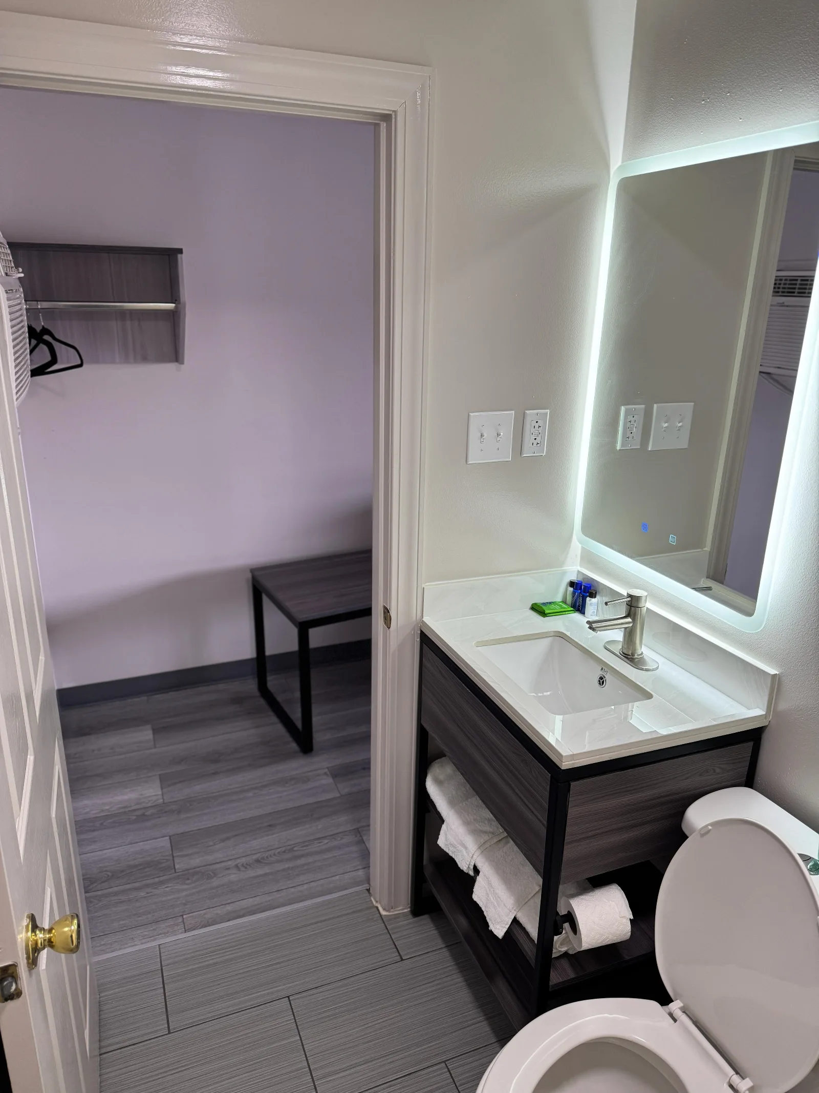 Modern bathroom with lighted mirror, vanity sink, and toilet at Sportsman Inn