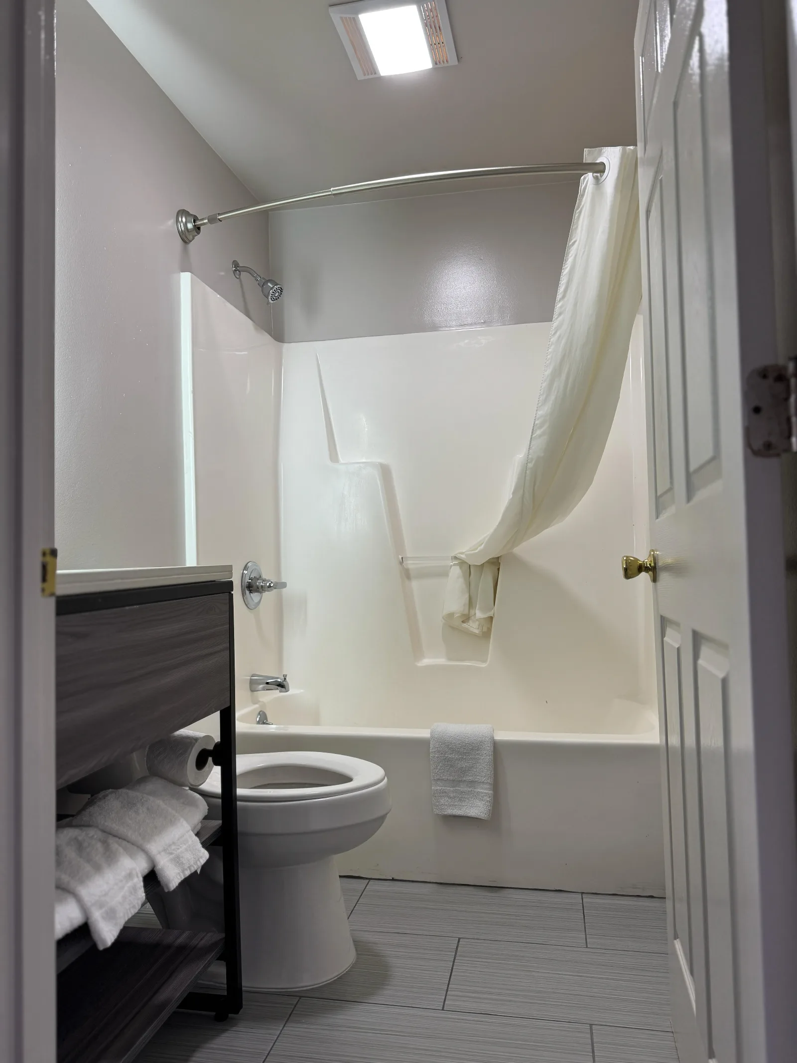 Clean bathroom with tub and shower, toilet, and attractive vanity at Sportsman Inn
