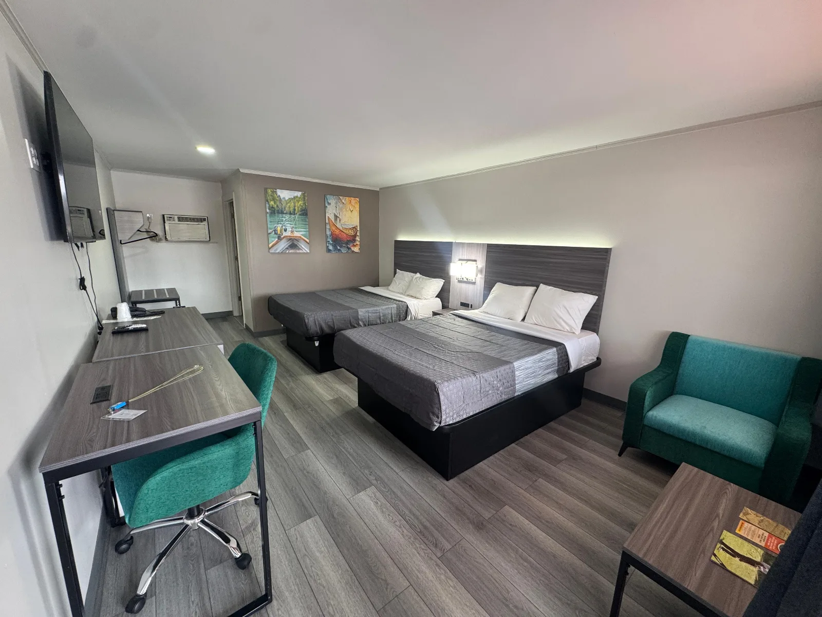 Superior Double Queen Room with two beds, teal chairs, desk, and flat-screen TV at Sportsman Inn