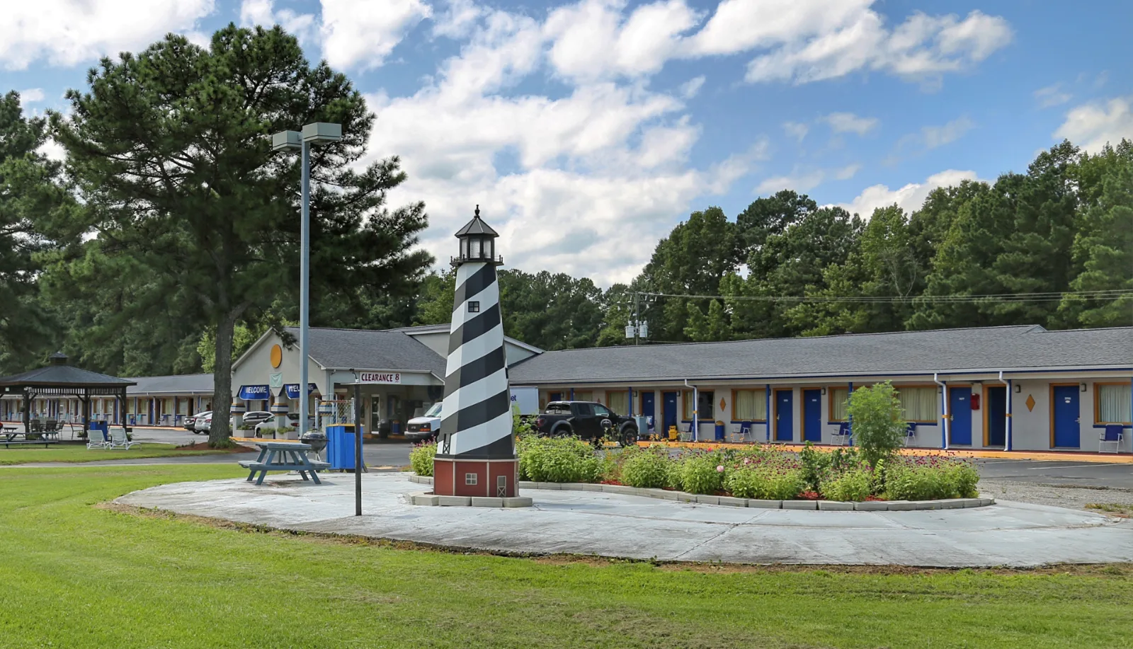 Striped lighthouse monument and motel exterior with blue doors at Sportsman Inn