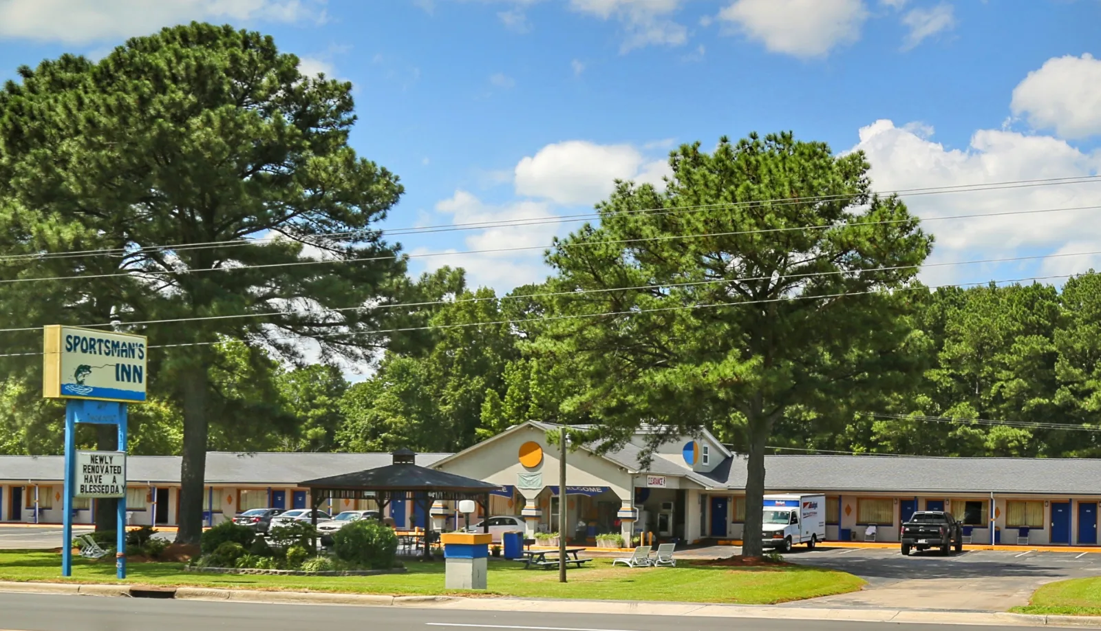 Sportsman's Inn exterior with blue signage, guest rooms, and shaded grounds in Plymouth, NC