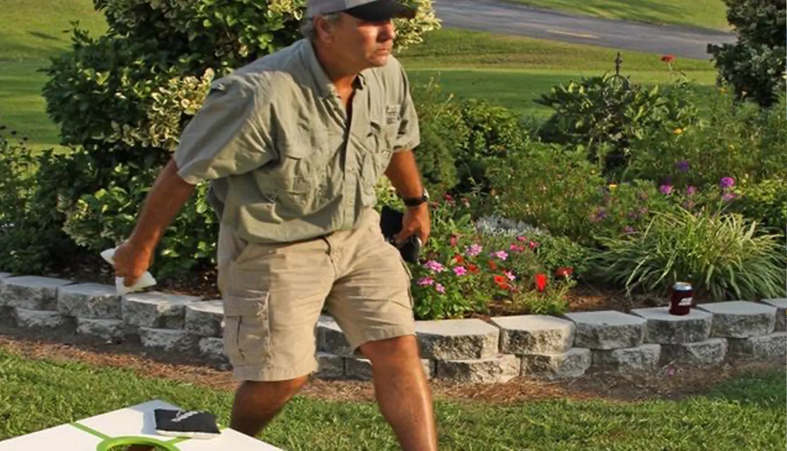 Man playing cornhole in landscaped yard at Sportsman Inn