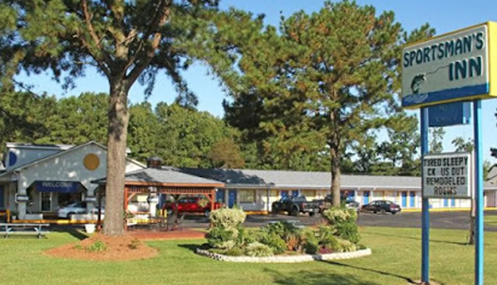 Sportsman's Inn exterior with sign, lawn, and pine trees in Plymouth, NC