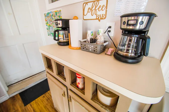 Sportsman Inn coffee bar with two coffee makers, supplies, and snacks at Sportsman Inn