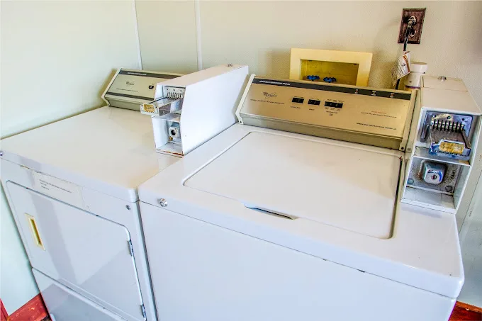 Coin laundry room with white washers and dryers at Sportsman Inn