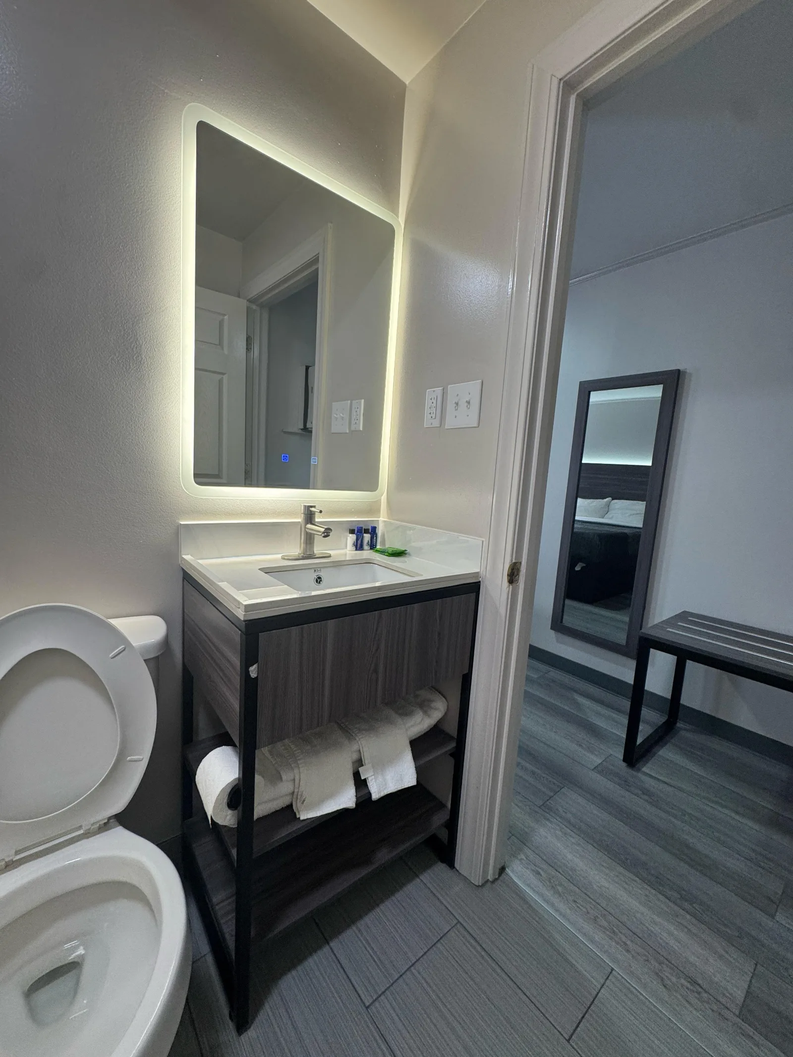 Modern bathroom vanity with illuminated mirror and dark wood cabinets at Sportsman Inn