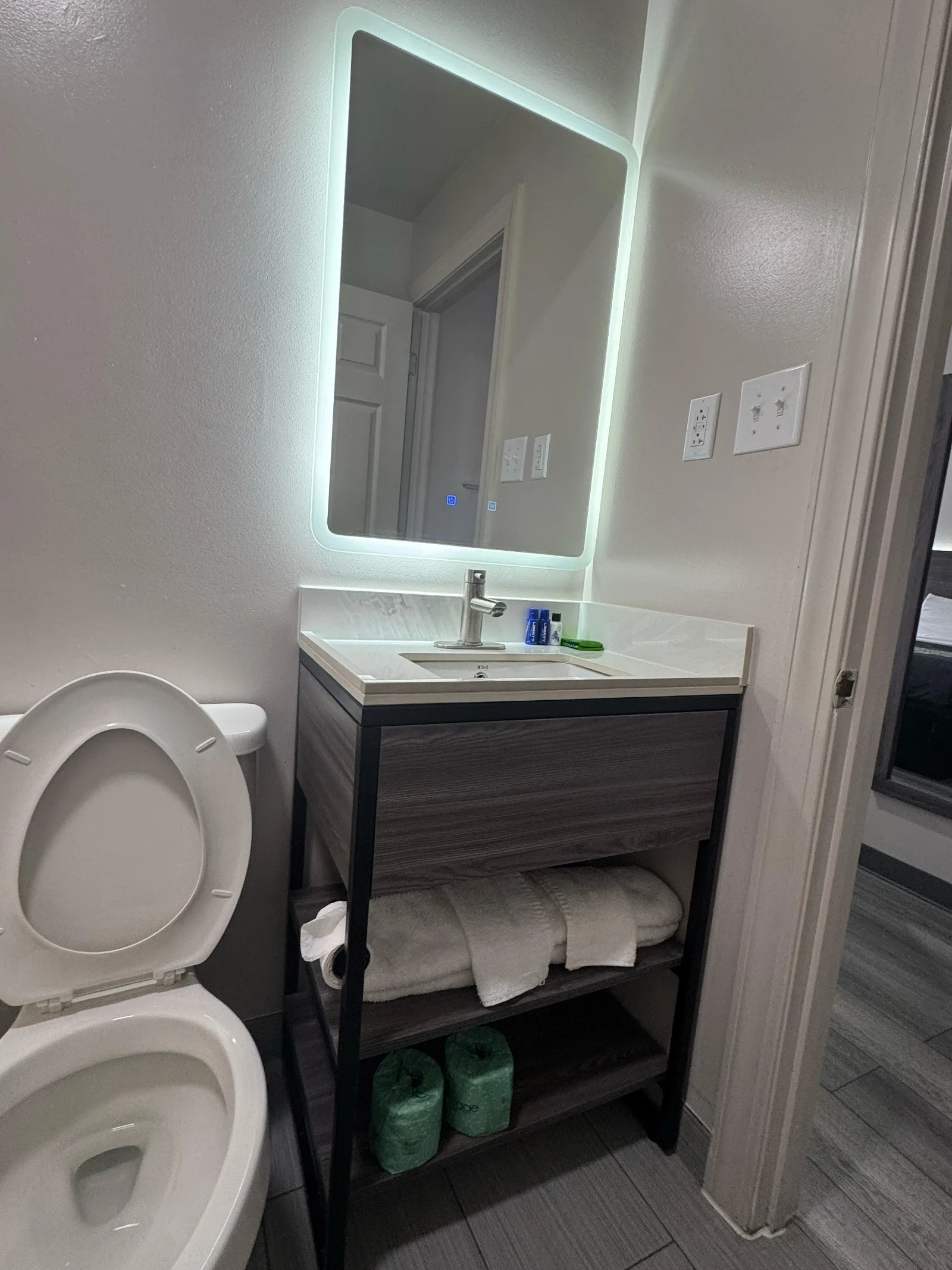 Modern bathroom vanity with illuminated mirror and dark wood cabinet at Sportsman Inn